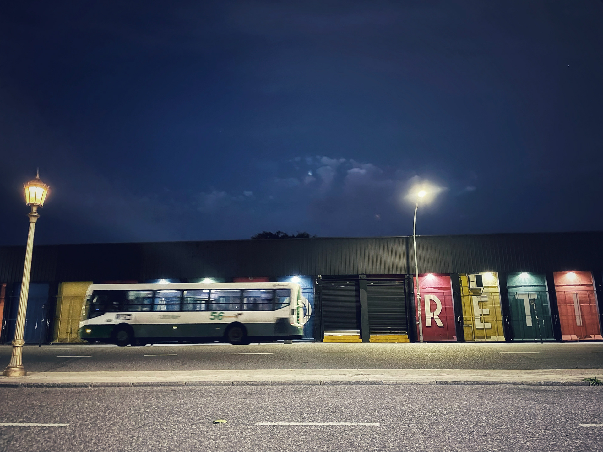 Bus passing a colorful Retiro building at night