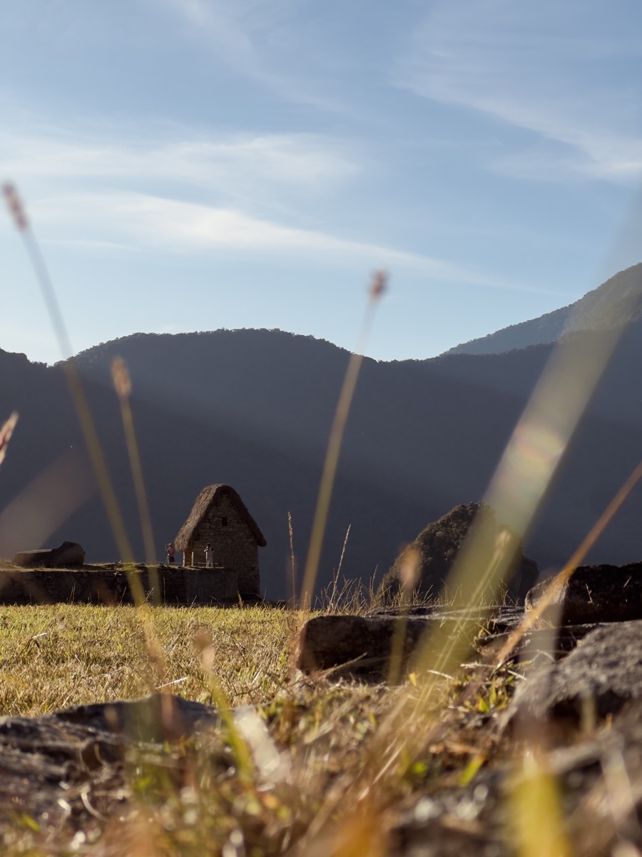 Stone hut among mountains and tall grass
